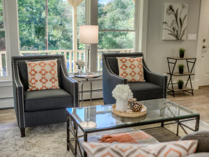 A pop of orange as the accent color dances throughout the living room staging of 776 Jackson Avenue, New Windsor by Claudia Jacobs Designs. Photo credit: Steve Belner, Photovisions