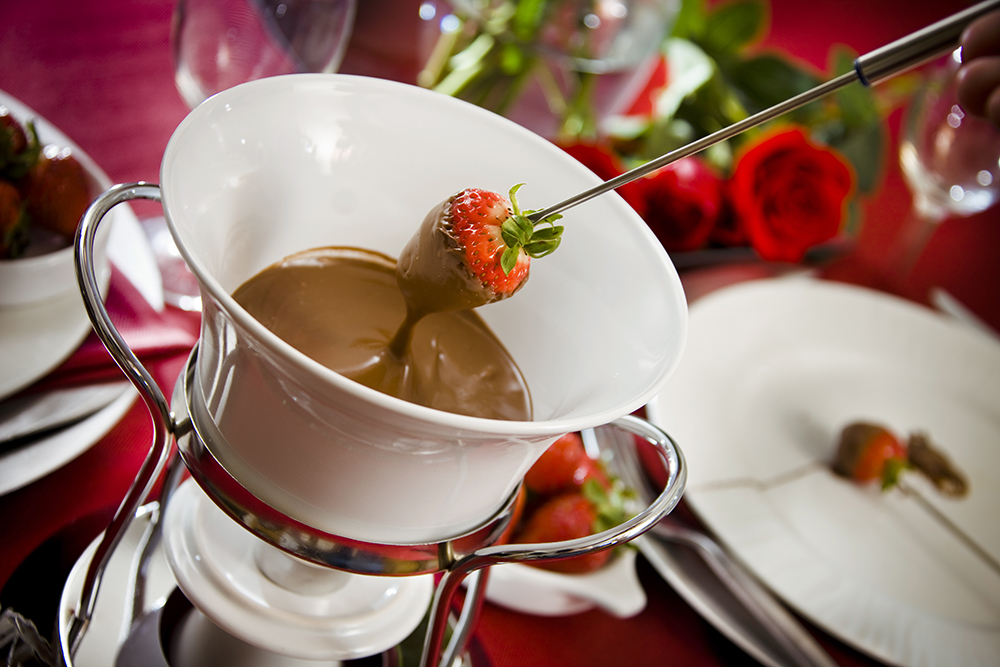 Strawberry being taken out of Chocolate fondue